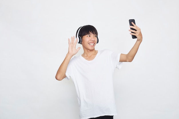 Jovem asiático usando fones de ouvido de um smartphone em branco