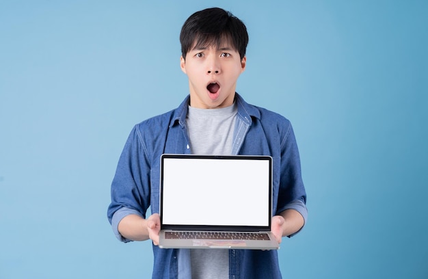 Jovem asiático usando laptop em fundo azul