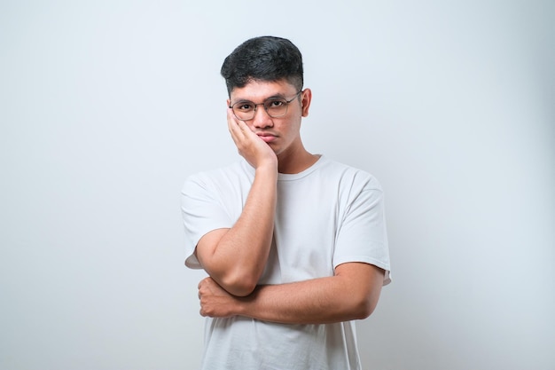 Jovem asiático vestindo camisa casual e óculos pensando parecendo cansado e entediado com problemas de depressão com braços cruzados