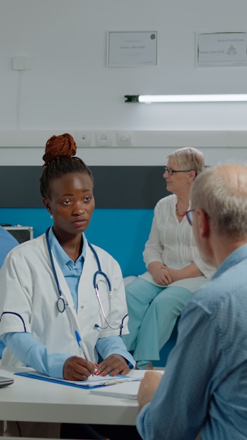 Jovem assistente médica dando raio-x a um médico sentado à mesa