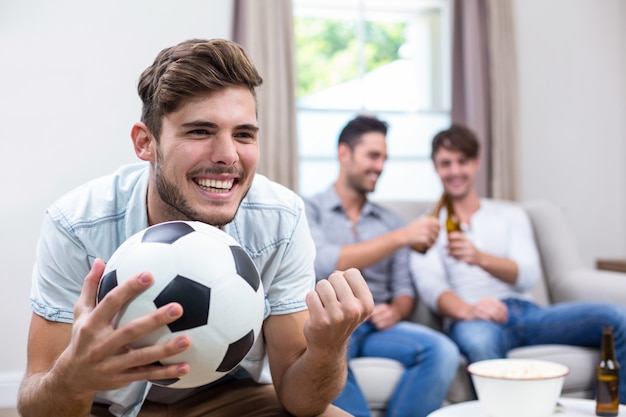 Jovem assistindo jogo de futebol enquanto amigos