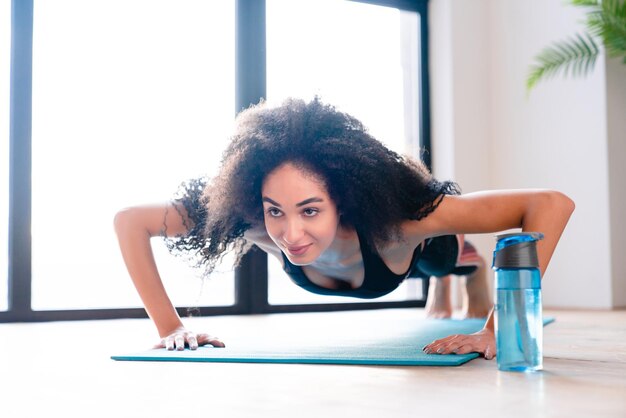 Jovem atleta africana atleta feminina desenvolvendo força física resistência emagrecimento e queima de calorias treino em casa ioga alongamento