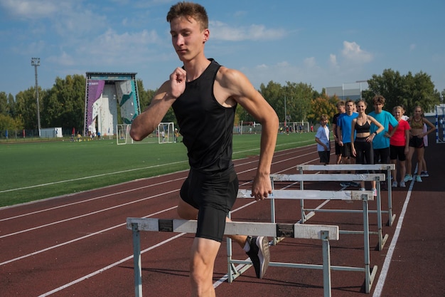 Jovem atleta corredor correndo obstáculos no estádio ao ar livre