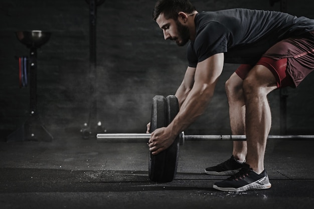 Foto jovem atleta de cross fit preparando barra para levantamento de peso na academia