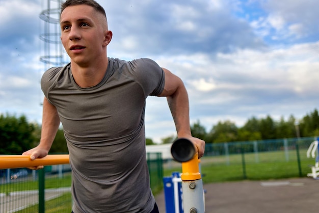 Jovem atleta de uniforme esportivo realiza exercícios de ginástica em barras paralelas