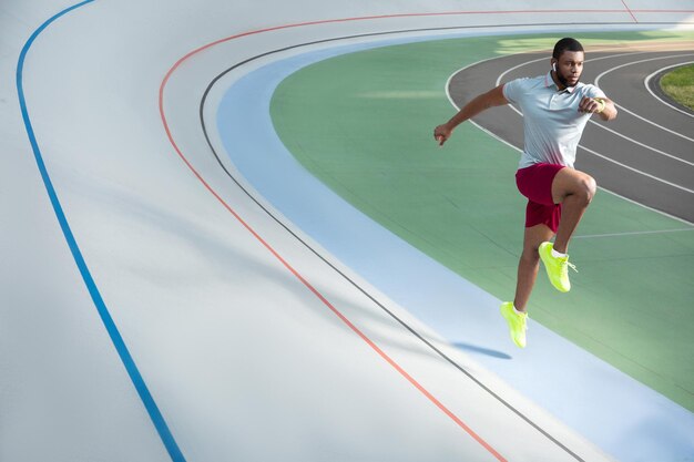 Foto jovem atleta do sexo masculino correndo na pista de corrida