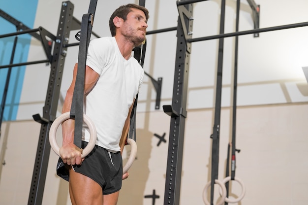 Jovem atleta do sexo masculino se exercitando com argolas de ginástica na academia