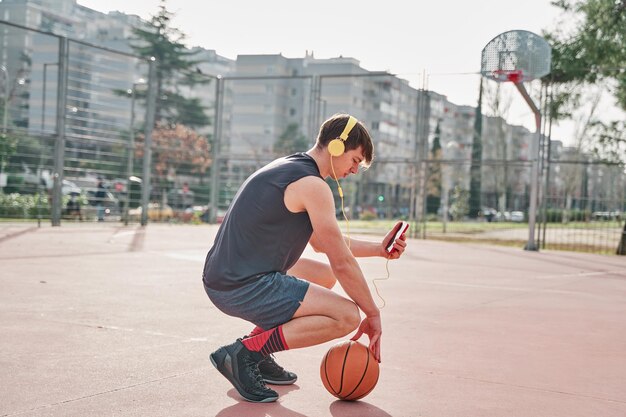 Jovem atleta em uma quadra de basquete treinando enquanto ouve música