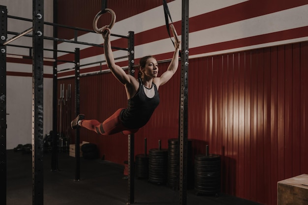 Foto jovem atleta feminina balançando em anéis de ginástica no ginásio