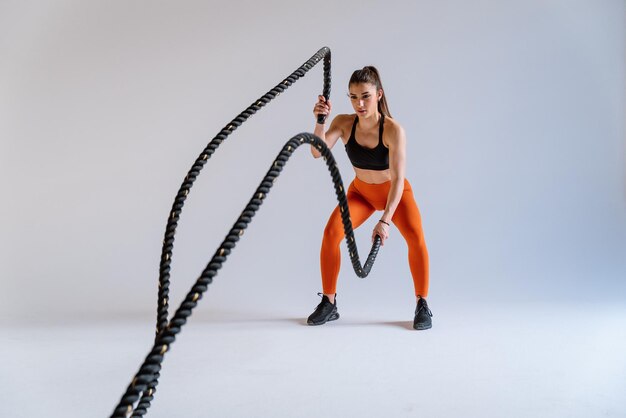 Jovem atleta feminina treinando em uma academia usando equipamentos esportivos