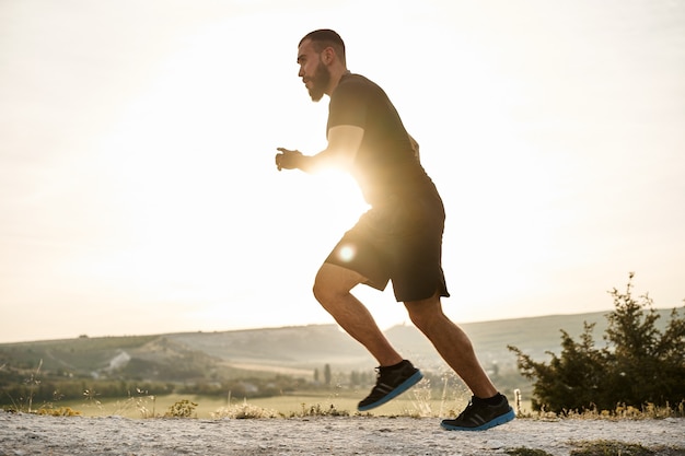 Foto jovem atleta masculino musculoso subindo a colina correndo