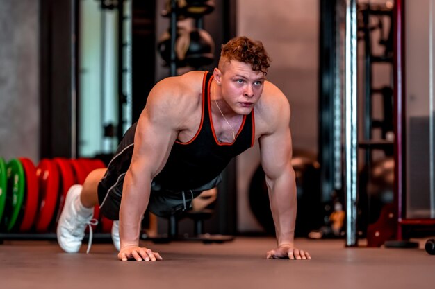 Jovem atleta realiza flexões no chão da academia