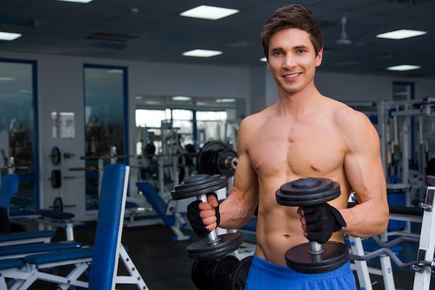 Jovem atleta sorridente levantando peso na academia e smail