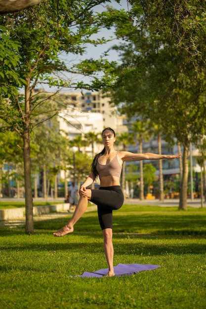 Jovem atlética fazendo ioga no parque pela manhã