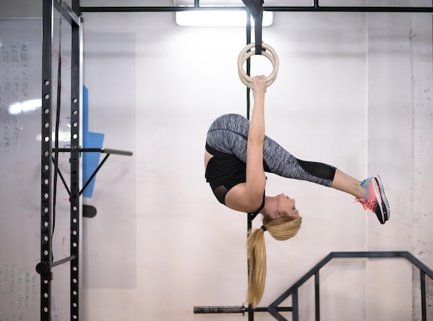 jovem atlética malhando nos anéis de ginástica no ginásio de fitness cross