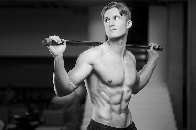 Foto jovem atlético bombando músculos na academia durante o treino esporte e conceito de saúde