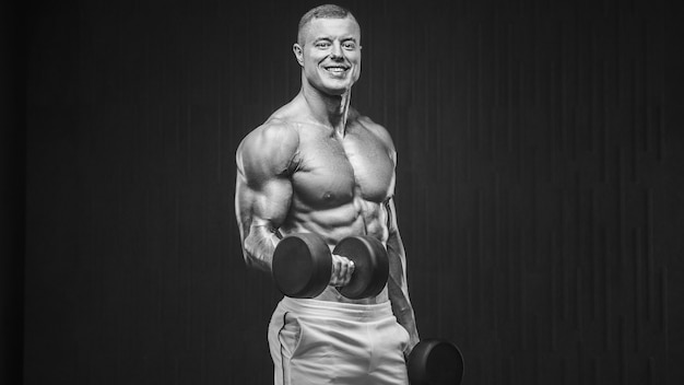 Foto jovem atlético bombando músculos na academia durante o treino esporte e plano de fundo do conceito de saúde