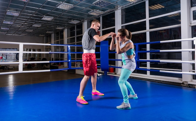 Jovem Atlético masculino e feminino em roupas esportivas em ação, praticando boxe no ginásio