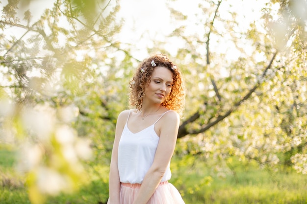 Jovem atraente caminha no parque verde primavera, apreciando a natureza de floração. Menina sorridente saudável girando no gramado da primavera. Alergia sem