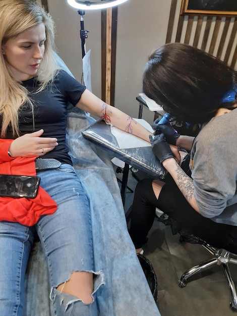 Jovem atraente caucasiana fazendo uma tatuagem no braço em um estúdio de tatuagem