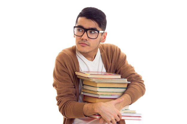 Jovem atraente com cabelo preto em camiseta branca cardigan marrom segurando uma pilha de livros