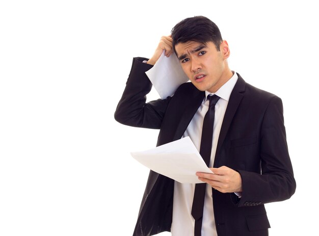 Jovem atraente com cabelo preto na camisa branca e terno preto com gravata preta segurando papéis