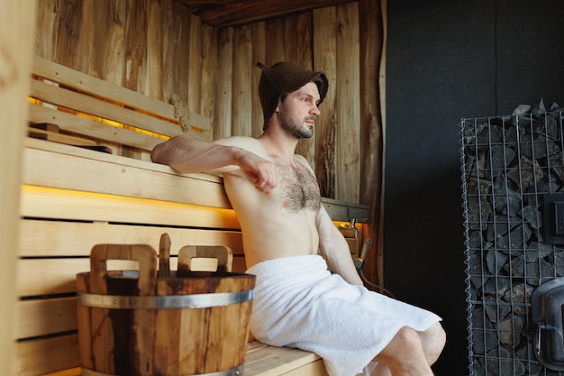 Jovem atraente com corpo musculoso relaxante na sauna