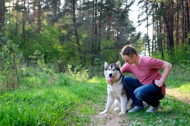 Jovem atraente com seu cão malamute em uma caminhada na floresta