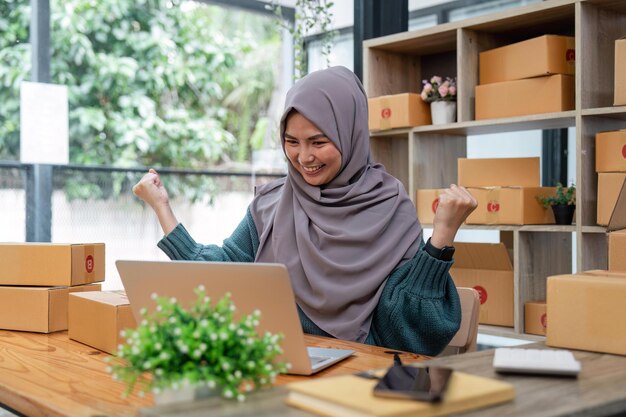 Jovem atraente e bela empresária muçulmana PME, proprietária de uma empresa comemorando uma vitória na venda on-line após um novo pedido do cliente