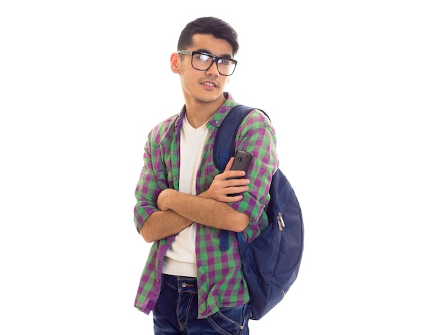 Jovem atraente em camiseta branca e camisa quadriculada com mochila azul segurando seu smartphone