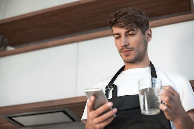 Jovem atraente lendo uma receita em seu smartphone