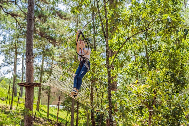 Jovem atraente no parque de corda de aventura em equipamentos de segurança