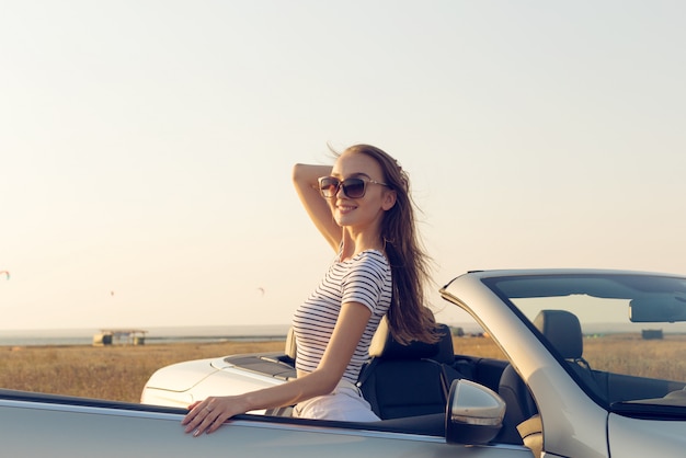 jovem atraente perto de um carro conversível