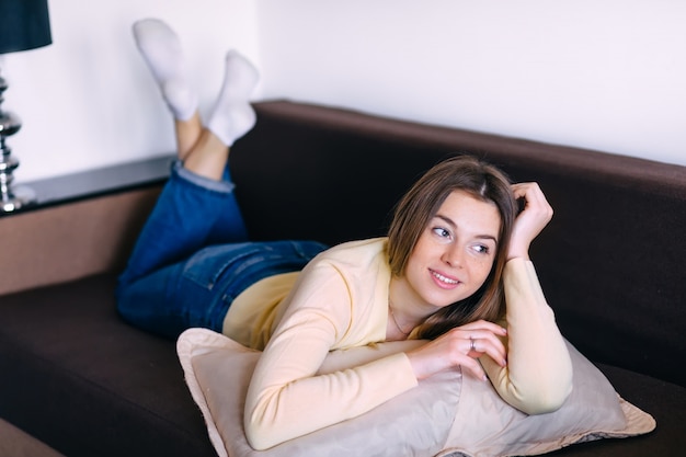 Jovem atraente, relaxando em um sofá e assistindo tv