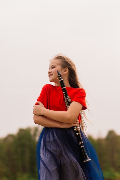 Jovem atraente tocando clarinete, ébano no parque de outono