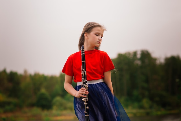 Jovem atraente tocando clarinete, ébano no parque de outono