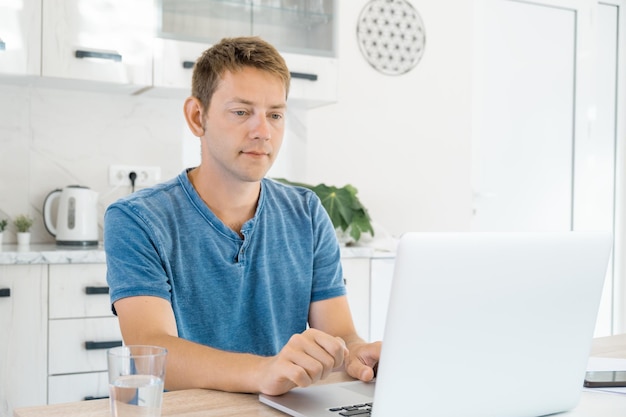 Foto jovem atraente trabalhando em laptop online em casa usando internet homem freelancer usando computador