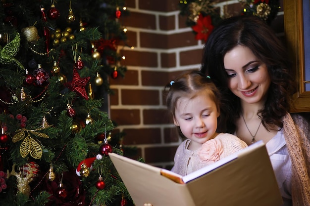 Jovem atraente vestindo pijama quente e uma colcha perto da atmosfera de natal da árvore de ano novo