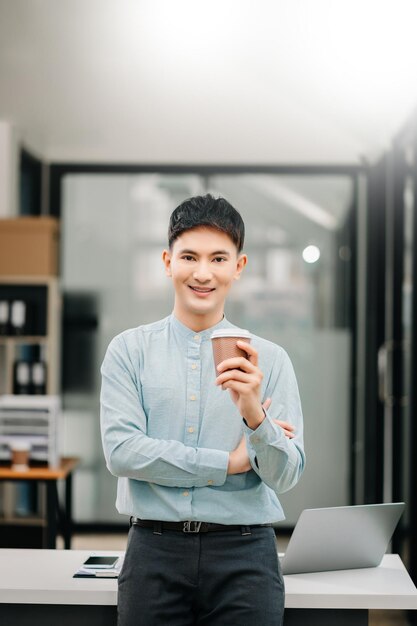 Foto jovem atrativo homem asiático trabalhador de escritório negócio sorrindo para a câmera em escritório moderno