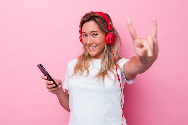 Jovem australiana ouvindo música isolada em fundo rosa