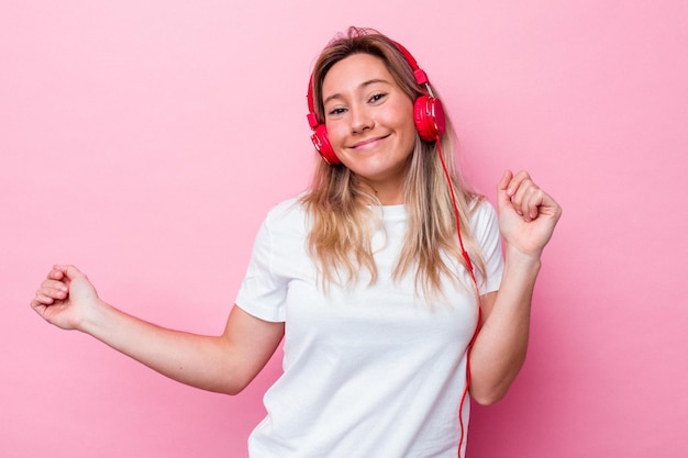 Jovem australiana ouvindo música isolada em fundo rosa