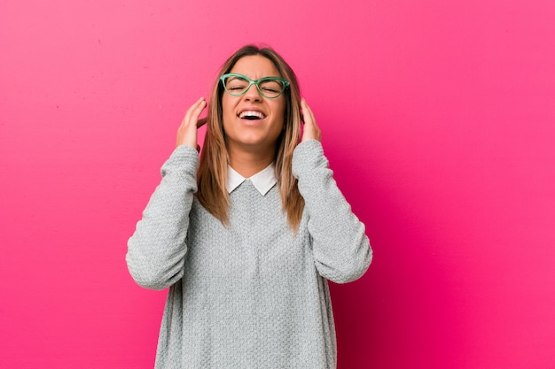 Jovem autêntica mulher carismática contra uma parede alegre rindo muito. Conceito de felicidade.