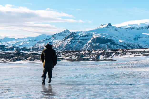 Jovem aventureiro caminhando para trás na geleira Vatnajokull no inverno na Islândia