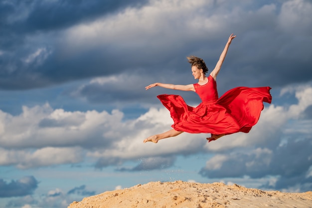 Jovem bailarina com um vestido longo vermelho dançando