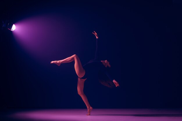 Jovem bailarina dançando no fundo do estúdio de luzes de néon. Projeto de bailarina com modelo caucasiano. O balé, dança, arte, contemporâneo, conceito de coreografia