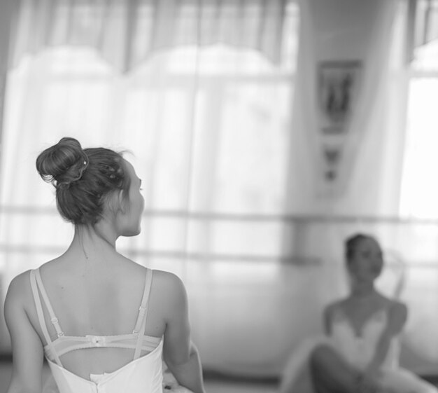 Jovem bailarina em um aquecimento. A bailarina se prepara para se apresentar em estúdio. Uma garota com roupas e sapatos de balé amassa pelo corrimão.
