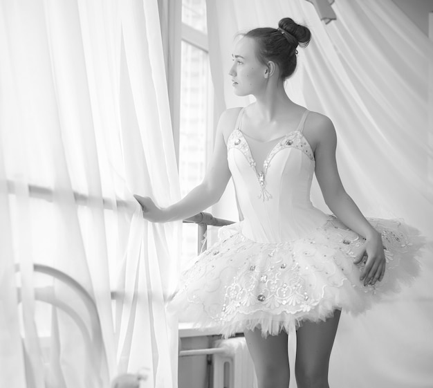 Jovem bailarina em um aquecimento. A bailarina se prepara para se apresentar no estúdio. Uma garota com roupas e sapatos de balé amassa pelo corrimão.