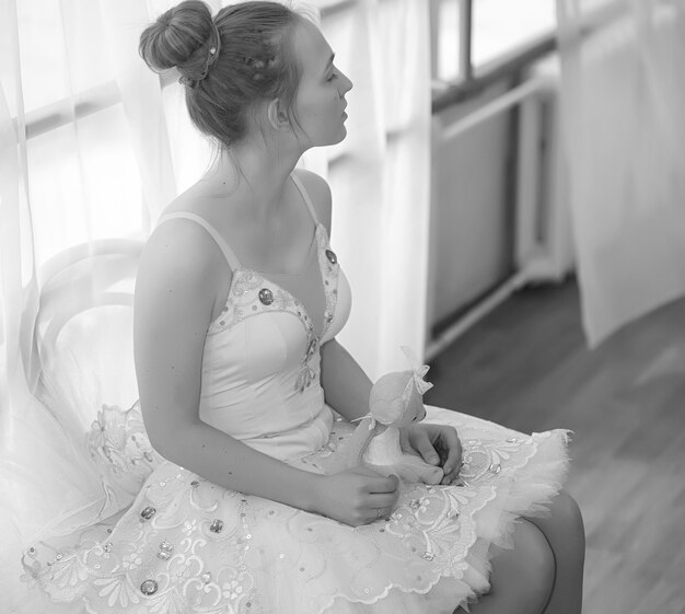 Jovem bailarina em um aquecimento. A bailarina se prepara para se apresentar no estúdio. Uma garota com roupas e sapatos de balé amassa pelo corrimão.