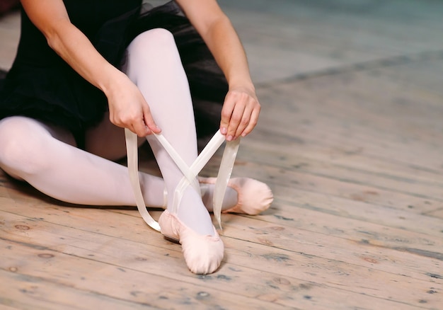 Jovem bailarina em vestido preto treina nos bastidores.