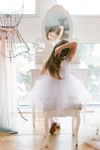 jovem bailarina linda senta-se em um pufe na frente de um espelho. Garotinha